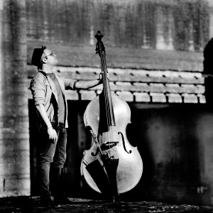 Adam Ben Ezra standing looking up holding his double bass.