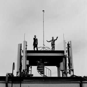 Gus Gus members Daniel Agust Haraldsson and Birgir Porarinsson posing on a broadcaster at the rooftop of the building with skies in the background.