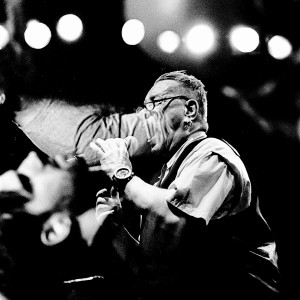 Double exposure of John Lydon Pil singing on the stage at his concert and people in the audience.