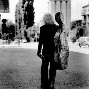 Misha Maisky from the back holding the cello case on the back.