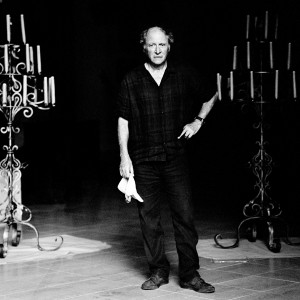 Robert Dornhelm standing and holding a handkerchief in his hand between two candlesticks.