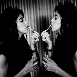 Samar Qupty putting lipstick in front of a mirror with her reflection.